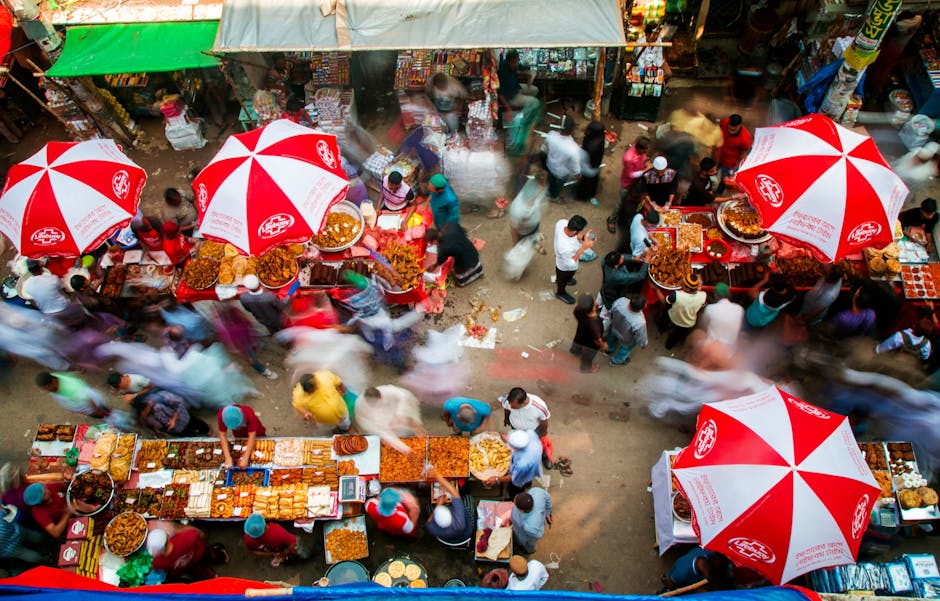 A colorful top view of a bustling outdoor market with food stalls and blurred motion of people.